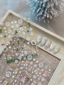 Close-up of 5D embossed Christmas nail stickers with gold foil trees and snowflakes