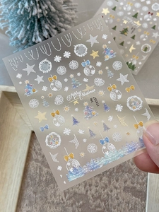 Detail of Christmas nail stickers with gold foil trees and snowflakes on a festive background