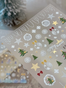 Close-up of embossed Christmas tree nail art stickers with gold foil snowflakes