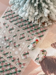 Detail of Christmas nail stickers with red plaid patterns, snowflakes and pearl decor