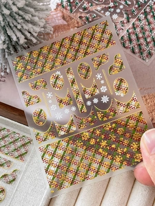 Close-up of gold embossed Christmas snowflake plaid nail art stickers with metallic texture