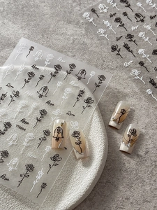 Macro detail of embossed rose nail stickers with black and white floral patterns