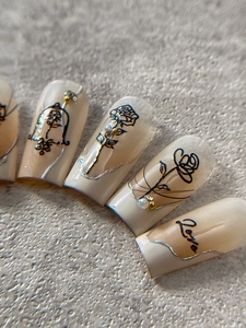 Macro detail of relief rose nail art stickers with vintage beads and pearl embellishments