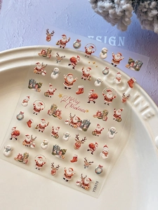 Macro shot of 3D embossed Christmas nail art stickers featuring Santa and reindeer designs