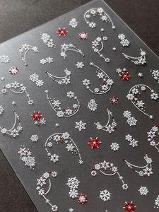 Makroaufnahme von 3D-Weihnachtsschneeflocken-Nagelstickern mit roten und weißen Perlenketten