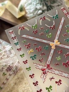 Détail d'autocollants ongles 3D de Noël avec nœuds rouges et motifs de dentelle