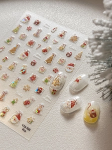 Detail of Christmas nail art stickers featuring Santa and reindeer on yellow gradient nails