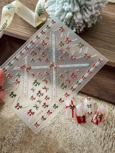 Détail de stickers à ongles 3D avec nœuds de Noël et motifs décoratifs rouges et verts