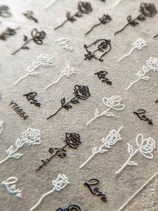 Macro detail of 3D embossed rose nail stickers and artistic text in black and white