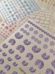 Detailed macro view of 5D embossed nail stickers with pearl purple spiral shell texture