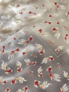 Detailed macro view of 3D embossed red and white koi fish nail stickers with glitter