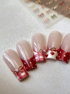 Detail of red and pink long trapezoid press-on nails with 3D bows and pearl accents