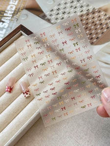 Close-up of colorful embossed bow nail stickers applied on various nail art designs