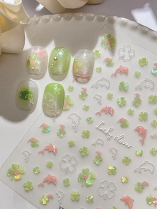 Macro detail of lucky clover and dolphin nail art stickers with glitter finish on nails