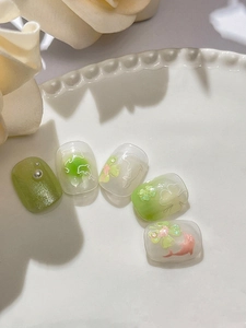 Macro shot of green clover and dolphin nail charms on polished press-on nail set