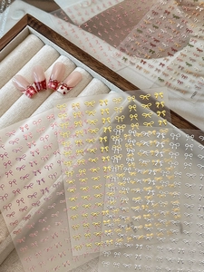 Macro view of 3D bow nail art stickers in various colors applied on red French manicure