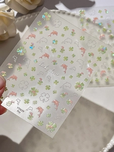 Detailed macro of holographic dolphin and clover nail stickers with shimmer finish
