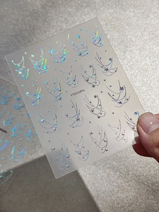 Close-up of holographic silver star chain nail stickers with linear decorative patterns
