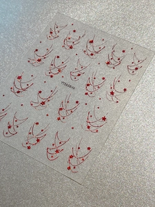 Macro detail of red star and wave pattern nail stickers on a sparkling silver background