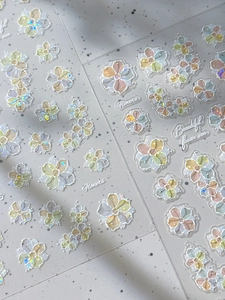 Macro shot of 3D shell flower nail art stickers with iridescent glitter and floral details
