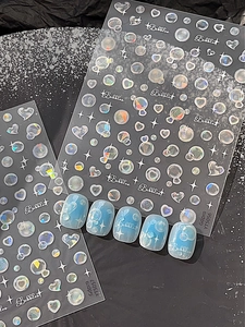 Détail de stickers à ongles bulles et étoiles avec effet laser holographique sur bleu