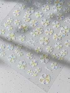 Close-up of 3D embossed flower nail stickers with iridescent pearl finish and 5-petal patterns