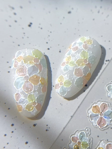 Detail of 3D macaron flower patterns on milky white press-on nails with embossed texture