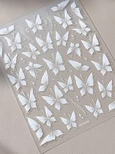 Close-up of white embossed butterfly nail stickers with stars on leather texture