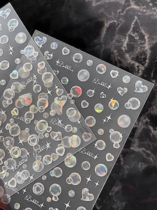 Vue macro de stickers à ongles holographiques avec motifs de bulles et cœurs sur noir