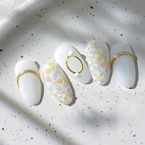 Floral press-on nails with white base, pearl accents and gold wire design on ceramic tray