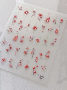 Vue détaillée d'autocollants pour ongles magnolia rouge avec accents de feuilles d'or