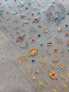 Macro shot of gold and silver sun and moon nail art stickers with bohemian patterns