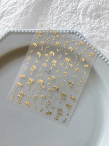 Macro detail of golden summer nail stickers with palm trees and birds on transparent sheet