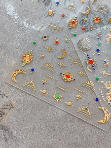 Detailed view of vintage gold nail art stickers with moon, sun, and jewel patterns