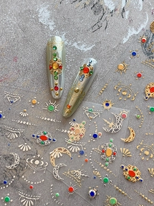 Macro view of gold foil moon and star nail stickers with colorful faux gemstone designs