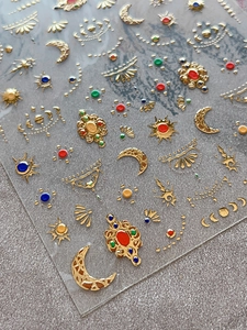 Macro view of gold embossed nail art stickers with celestial sun and moon motifs