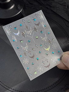 Macro shot of laser holographic spider and bat nail art stickers for Halloween