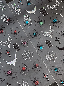 Macro detail of embossed Gothic nail stickers with colorful glitter spiders and bats