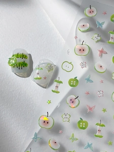 Macro shot of 3D laser apple and butterfly nail art stickers with iridescent shell effect