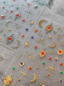 Macro detail of 3D metallic relief nail stickers with sun, moon and crown patterns