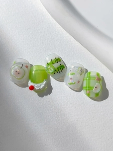 Detail view of 3D green apple nail charms and plaid patterns on glossy press-on nails