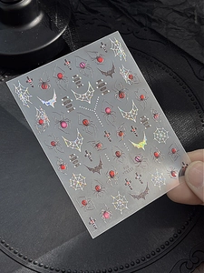 Detailed view of Halloween nail art stickers with red spiders and laser star patterns