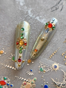Macro view of metallic silver nail art stickers with colorful rhinestones and gold totems