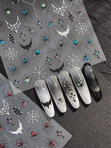 Detail of Halloween nail art stickers with spider, bat, and cross motifs in dark gothic style