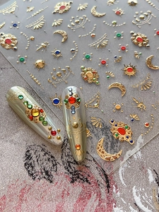 Detail of gold foil nail stickers with colorful rhinestones and bohemian sun motifs