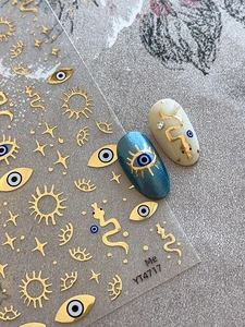 Detail of gold embossed nail decals featuring evil eye, snake, and star patterns