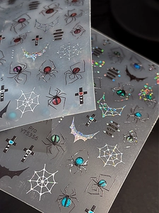 Macro shot of spider web nail stickers with holographic glitter and cross patterns