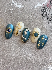 Detail of luxury press-on nails featuring evil eye, golden snake and star motifs