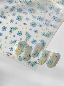 Detailed view of blue floral nail stickers and finished art with yellow core accents