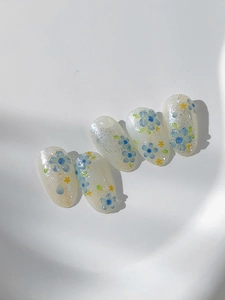 Detail of five-petal flower nail art decals with pearlescent finish and glitter accents